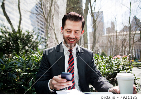 Businessman looking at smartphone and smiling 7921135