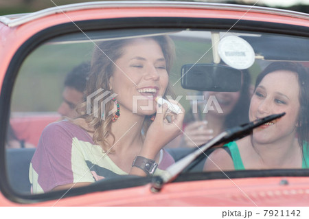 Woman applying lipstick in convertible Woman applying lipstick in convertible 7921142