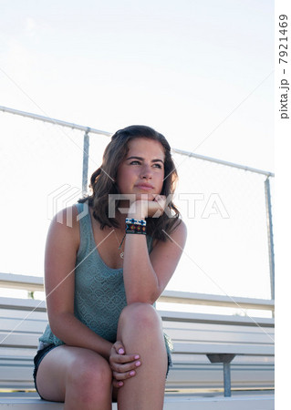 Teenage girl sitting on bleachers with hand on chin, portrait Teenage girl sitting on bleachers with hand on chin, portrait 7921469