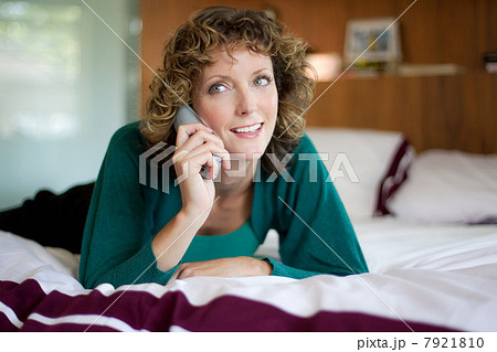 Mid adult woman using telephone in bedroom 7921810