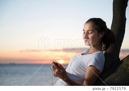 Close up of young woman leaning on tree at dusk 7922579
