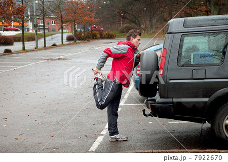 Mature man stretching against car in car park 7922670
