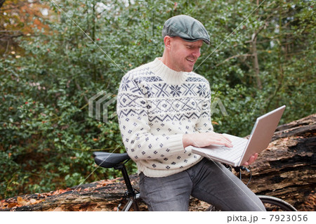 Man outdoors with laptop and bike 7923056