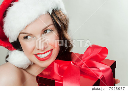 Young brunette woman wearing Santa hat with Christmas present 7923077