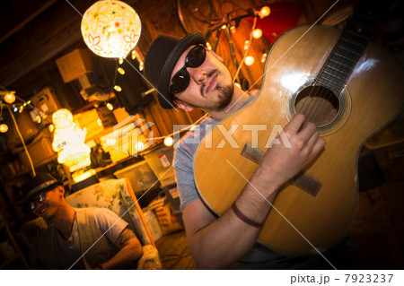 Man wearing hat and sunglasses playing guitar 7923237