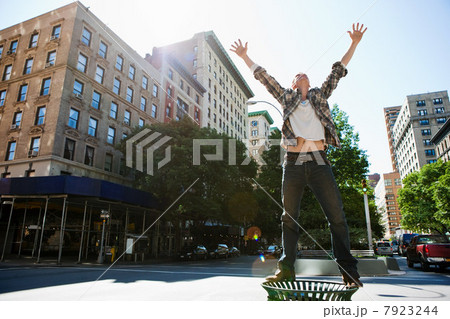Mid adult man standing on litter bin in city Mid adult man standing on litter bin in city 7923244