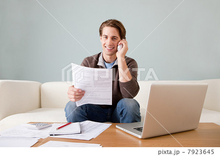 Young man with paperwork using laptop 7923645