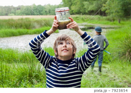 Boy looking at tadpoles in jar Boy looking at tadpoles in jar 7923654