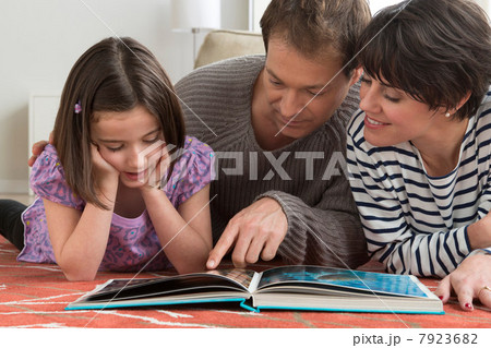 Daughter looking at picture book with parents 7923682