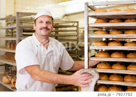 Baker in his bakery baking bread 7927702