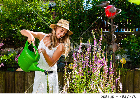 Woman gardener watering flowers in garden 7927776
