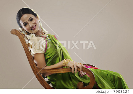 South Indian woman sitting on an arm chair South Indian woman sitting on an arm chair 7933124