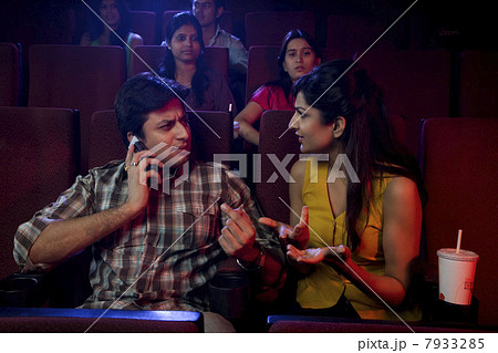 Man talking on a mobile phone in a cinema hall Man talking on a mobile phone in a cinema hall 7933285
