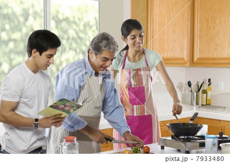 Father cutting vegetables while his daughter cooks Father cutting vegetables while his daughter cooks 7933480