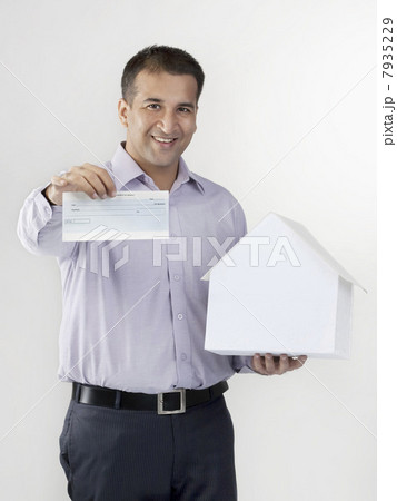 Man holding a house model and cheque 7935229