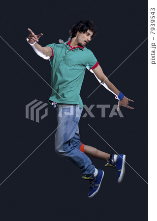Young man in casual clothing dancing over black background Young man in casual clothing dancing over black background 7939543