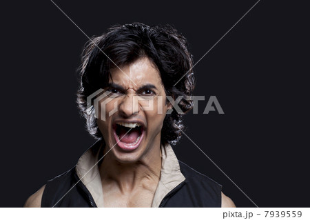 Portrait of young man screaming against black background 7939559