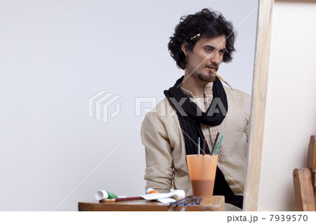 Young artist contemplating with paintbrush in mouthYoung artist contemplating with paintbrush in mouth 7939570