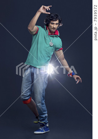 Full length of a young Indian man dancing with spotlight in background 7939572