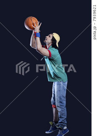 Full length of young man throwing basket ball against black background 7939621