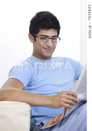 Happy young Indian man reading newspaper at home 7939845