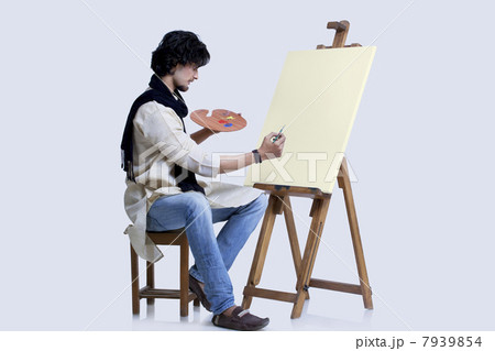 Young male artist about to paint against colored background 7939854