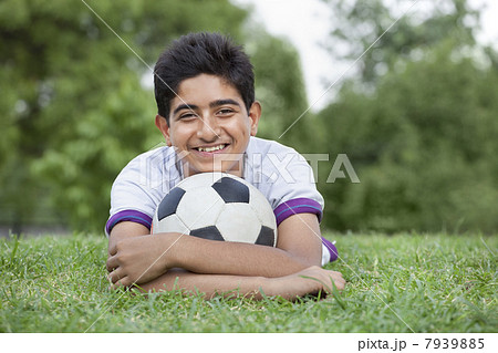 Portrait of young teenage boy with soccer ball lying on grass 7939885