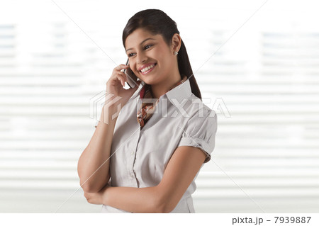 Smiling young businesswoman speaking on phone call at office 7939887
