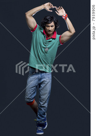 Full length of young Indian man with arms raised against black background 7939906