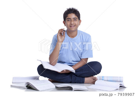 Portrait of teenage boy sitting on floor cross-legged studying against white background 7939907