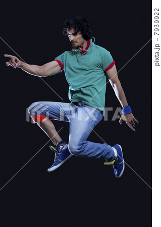 Young man in casual clothing jumping with rock and roll sign 7939922