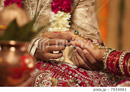 Close-up of a groom putting a wedding ring on a bride Close-up of a groom putting a wedding ring on a bride 7939961
