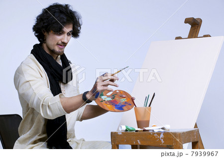 Handsome young artist near easel against colored background Handsome young artist near easel against colored background 7939967