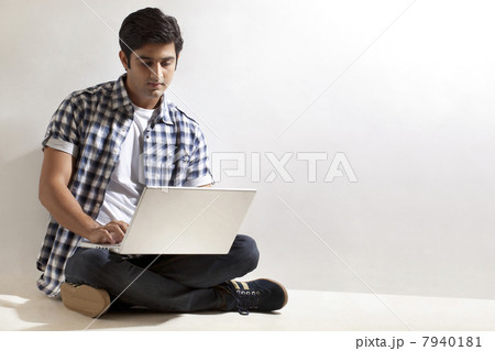 Young man sitting on floor with laptop 7940181