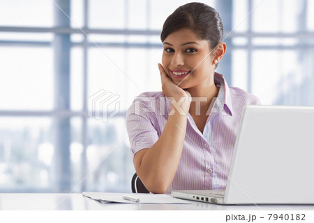 Portrait of smiling business woman at her desk with laptop 7940182