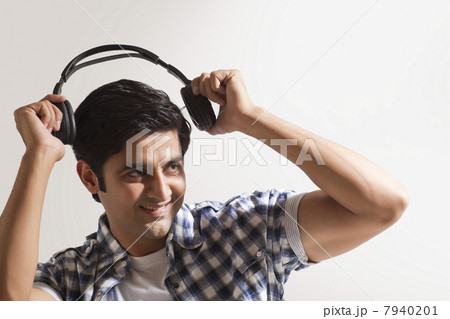Handsome young man holding headphones and smiling 7940201