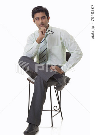 Handsome young executive sitting on chair and looking away 7940237