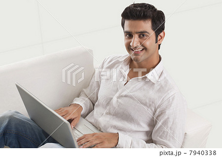 Relaxed young man on sofa using laptop 7940338