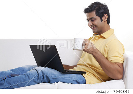Handsome young man using laptop while having coffee 7940345