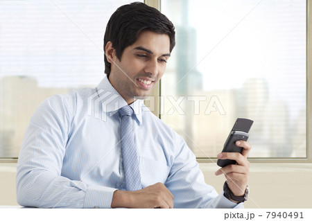 Happy young male executive reading text message 7940491