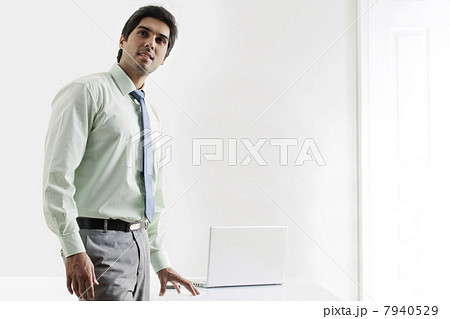 Confident businessman standing nearby laptop 7940529