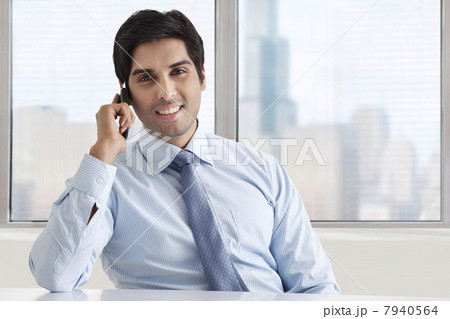 Portrait of smiling businessman speaking on phone call at office 7940564