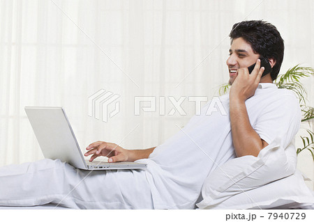 Smiling man having conversation while using laptop at home 7940729