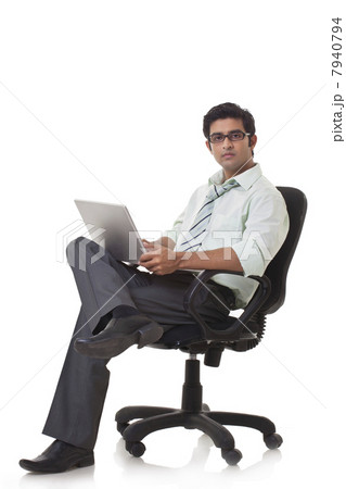 Portrait of male executive on office chair using laptop 7940794