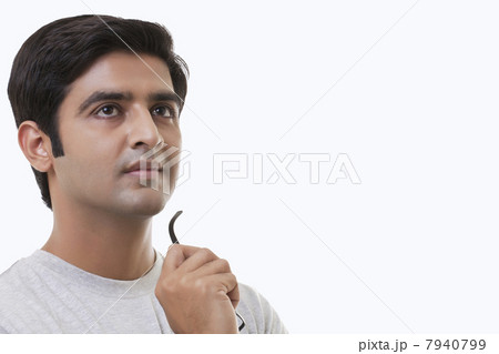 Thought young man holding glasses over white background 7940799