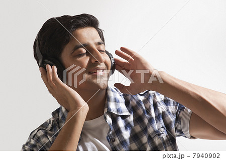Relaxed young guy listening music over colored background 7940902