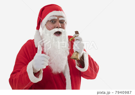 Front view of Santa Claus showing thumbs up while eating chocolate bar over white background 7940987