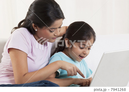 Mother assisting daughter using laptop 7941268