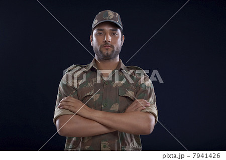 Portrait of a soldier standing with his arms crossed over blue background 7941426