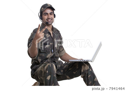 Portrait of soldier showing peace sign while using laptop Portrait of soldier showing peace sign while using laptop 7941464